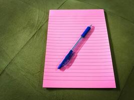 Top view of pink notebook with pencil placing over it photo