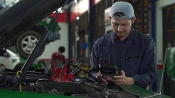 Asian auto mechanic checking battery voltage maintenance With a digital battery tester video