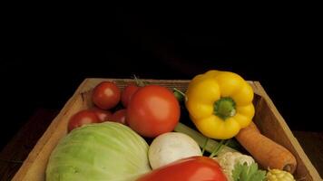 A wooden box is overflowing with a variety of fresh vegetables, showcasing a colorful and diverse selection of produce. Yellow and red bell peppers and corn are placed in a box. video