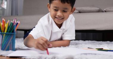 Front view of happy little asian boy lying on warm floor with underfloor heating video
