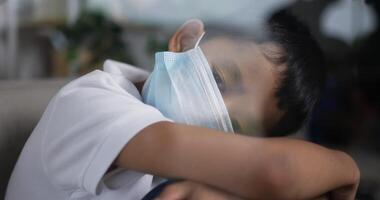 Boy wearing mask with head on knees looking out of the window. video