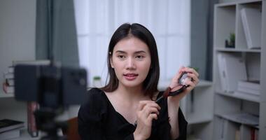 Handheld shot, Beautiful asian woman blogger is showing how to makeup and use cosmetics. In front of the smartphone to record vlog video live streaming at home. Influencer and cosmetics concepts.