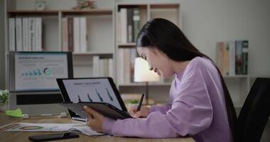 cenas do jovem ásia mulher, freelance dados cientista trabalhos remotamente às casa codificação programação em grande dados mineração, ai dados Engenharia, fêmea escreve notas em tábua. isto técnico. teletrabalho conceito. video