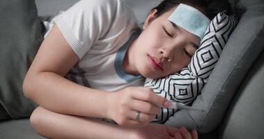 Footage steady shot, Unwell young woman have a fever and measure temperature with a thermometer while lying on sofa in the living room at home, healthcare woes video