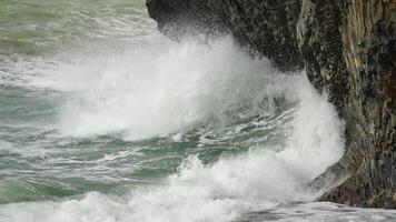 Stormy sea on sunset. The waves crash into the volcanic basalt rock, lit by the warm sunlight. Big wave breaks into splashes and white foam. Never-ending beauty of nature. Slow motion. video