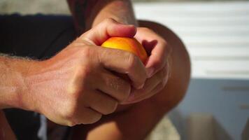 Man eating peach. Bearded man in sunglases eating peach on the beach. Happy man is smiling and resting at sea. Bearded guy enjoying fruits on summer vacation. Vegetarian and healthy lifestyle concept. video