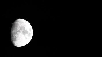 Timelapse. A glowing huge moon as seen from earth through the atmosphere against a starry night sky. A large moon moves across the sky, the moon moving from the left frame to the right. video