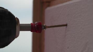 A man hands using a power tool fastens a board with a screw. Slow motion video