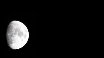 Timelapse. A glowing huge moon as seen from earth through the atmosphere against a starry night sky. A large moon moves across the sky, the moon moving from the left frame to the right. video