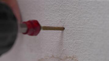 A man hands using a power tool fastens a board with a screw. Slow motion video