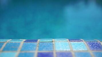Pool water background with wavy clear fresh water. Calm rest on sunny day. Abstract reflections on the surface of the water with texture of bright blue pool tiles. Turquoise water surface. Slow motion video