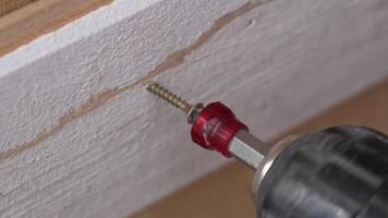 A man hands using a power tool fastens a board with a screw. Slow motion video