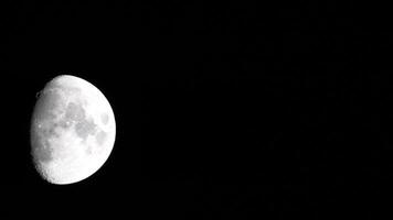 Timelapse. A glowing huge moon as seen from earth through the atmosphere against a starry night sky. A large moon moves across the sky, the moon moving from the left frame to the right. video