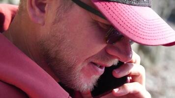 A young man with a beard, dressed in casual clothes smiles while talking on a mobile phone. video