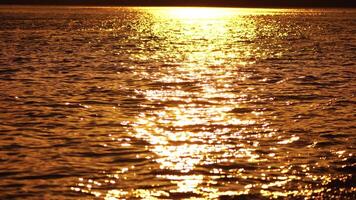 Blurred golden sea at sunset with shifting focus and bokeh effect. Sun reflects and sparkles on waves, illuminating golden sea. Holiday recreation concept. Abstract nautical summer ocean sunset nature video
