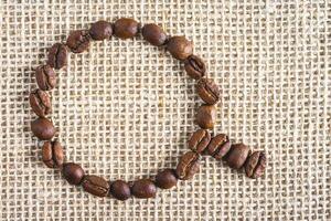 Coffee beans in the shape of a cup, on a burlap fabric. Background voor coffee related products. photo