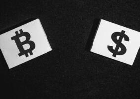 Two sticky notes on a black background with a bitcoin and a dollar on it. photo