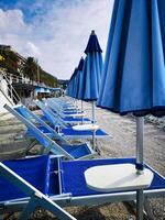deckchairs and umbrellas lined up on a beach on the Ligurian coast in the summer of August photo