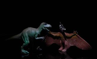 two dinosaurs, a velociraptor and a pterodactyl fight in a prehistoric scenario in a realistic way photo