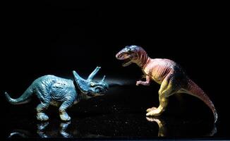 two dinosaurs, a tyrannosaurus rex and a triceratops fight in a realistic prehistoric setting illuminated by the moon photo