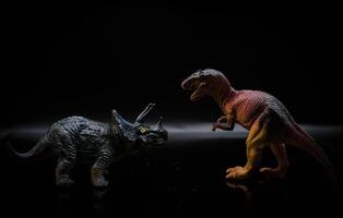 two dinosaurs, a tyrannosaurus rex and a triceratops fight in a realistic prehistoric setting illuminated by the moon photo