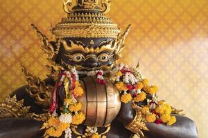 Rahu, the demon who causes eclipses, In Thailand, it is believed that this demon eats the moon, causing a lunar eclipse. He is eating spheres and with flowers in his hand. photo
