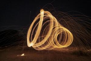 Spinning and burning Steel wool sparkle fire in the circle shape with long speed shutter shoot glowing light line to the ground. photo