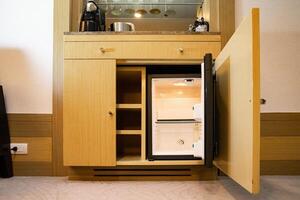 a refrigerator under the bar counter, according to the appearance of the refrigerator, it is a small size that is found only at the hotel, and can only hold a limited amount of stuff. photo