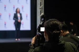 Asian man Videographer in backside are shooing and recording in Speech event on the stage. photo