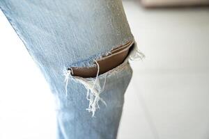 Jeans torn or ripped jeans Asian female leg, focus and close up to the knee. photo