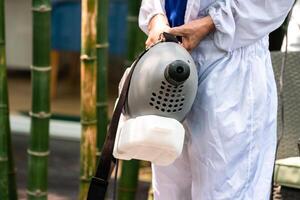 Professional technical man in prevention suit with his sterilizing machine and disinfecting water sprays in toilet or wc area field for purifying coronavirus COVID-19 photo