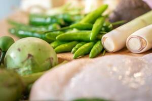 Focusing on green bird chillies is surrounded by eggplants, lemongrasses ,and others ingredients. photo