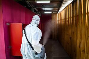 Professional technical man in prevention suit with his sterilizing machine and disinfecting water sprays in toilet or wc area field for purifying coronavirus COVID-19 photo