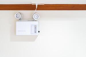 Automatic EMERGENCY LIGHT in hospital is charging and power pluging on the wall that ready to use when the power went out. photo