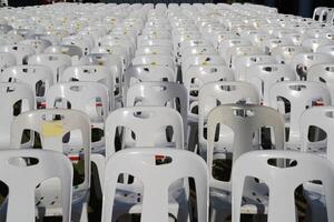 Many white plastic chairs were set up in a square area with the row and column for outdoor concerts or open air events. photo