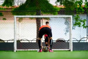 An athlete in reddish black has placed a ball in the center of the field. After receiving the coach's signal, he was about to prepare for the free kick. photo