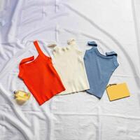 On the white sheet were three tank tops, red, white and blue, interspersed with perfume, model and notebook. photo