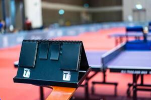 A tennis table black scoreboard is placed next to the table tennis table for referee count the score, which acts as a blurred background of pingpong tournament. photo