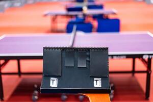 A tennis table black scoreboard is placed next to the table tennis table for referee count the score, which acts as a blurred background of pingpong tournament. photo