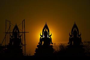 Silhouette Buddha statue between creating and building process, at outdoor field with the sun set and twilight period time., Thailand. photo