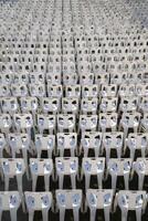 Many white plastic chairs were set up in a square area with the row and column for outdoor concerts or open air events. photo