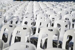 Many white plastic chairs were set up in a square area with the row and column for outdoor concerts or open air events. photo
