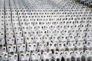 Many white plastic chairs were set up in a square area with the row and column for outdoor concerts or open air events. photo
