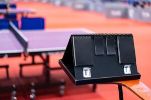 A tennis table black scoreboard is placed next to the table tennis table for referee count the score, which acts as a blurred background of pingpong tournament. photo
