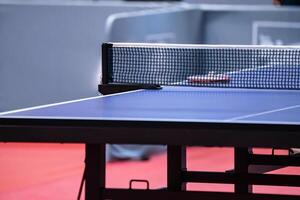 Blue and smooth surface table tennis table with tight black net to being prepared for practice and competition. photo