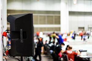 The black speaker set against a white wall with blurred background is used for voice acting in sports stadiums. The sound is clear and loud, so the action of the match can be heard clearly. photo