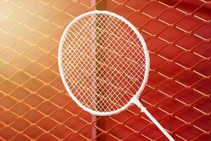 one badminton racket is hung on red grill by a cable tie for display in exhibition sports event photo
