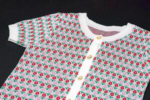 flat White knitwear pink red flower pattern sweater tshirt shape with pearl and gold circle buttons on black background with studio light photo