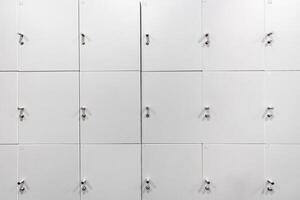 Large gray locker with each locker closed located beside corridors inside building are dimly lit. photo