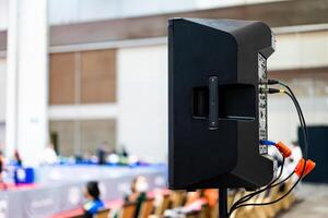 The black speaker set against a white wall with blurred background is used for voice acting in sports stadiums. The sound is clear and loud, so the action of the match can be heard clearly. photo